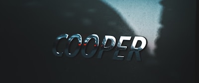 A close-up view of the word 'COOPER' in shiny metallic letters on a dark, glossy surface.