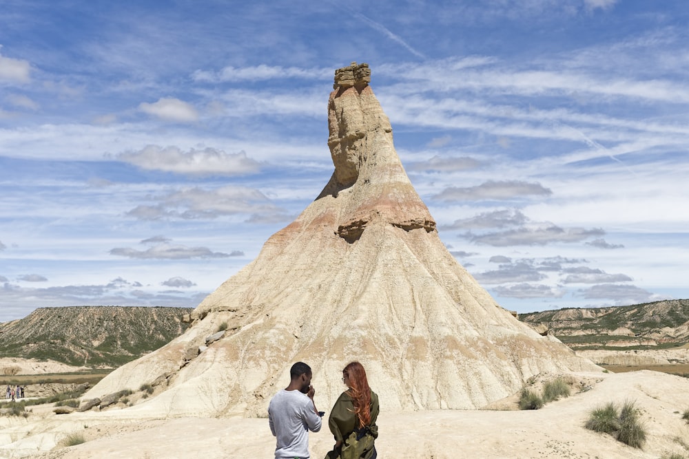 man and woman standing near gray cliff