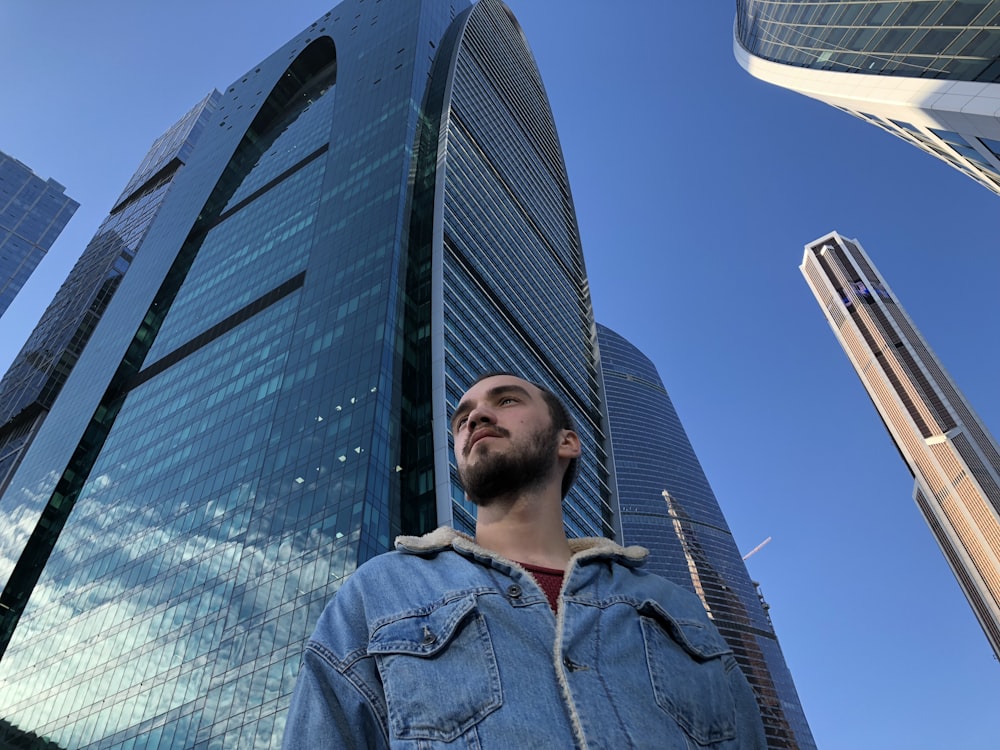 low-angle photography of man standing near high-rise glass buildingsx