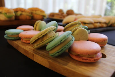 Assortment of colorful macarons and pastries arranged on a sleek black platter with neon highlights.