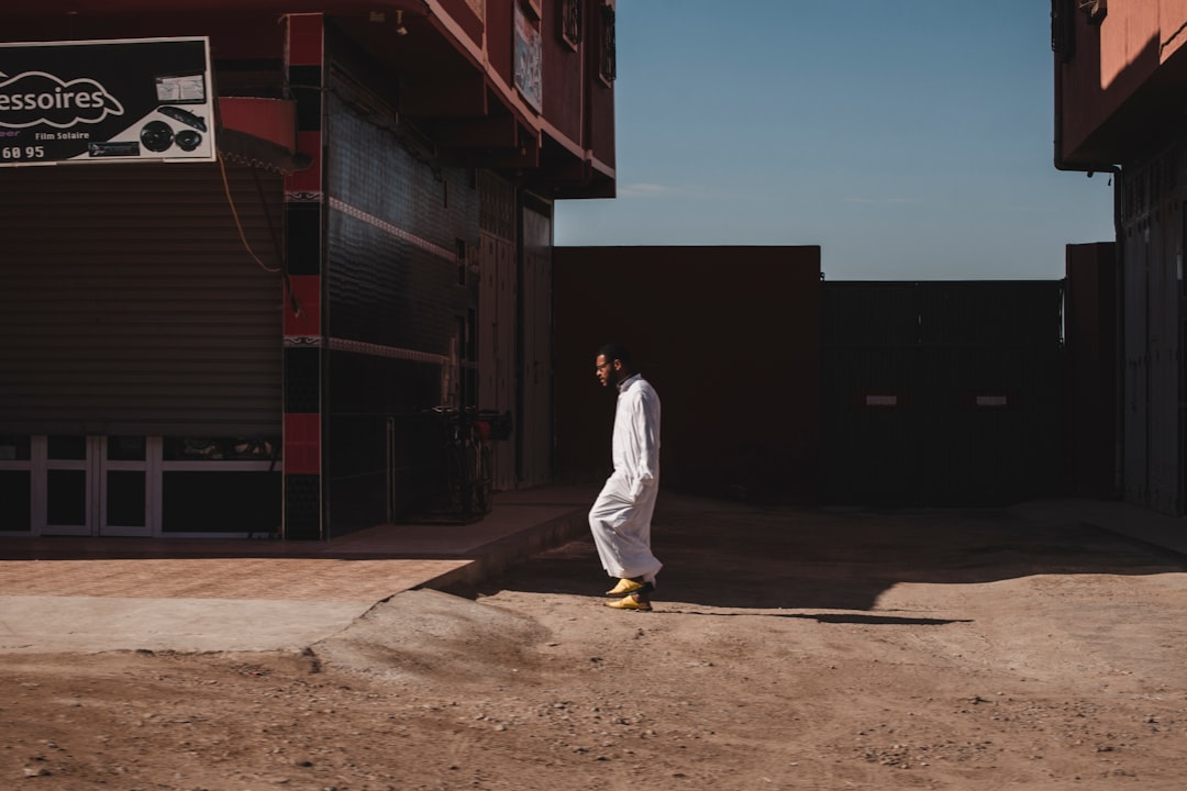 man wearing white thobe robe walking near building