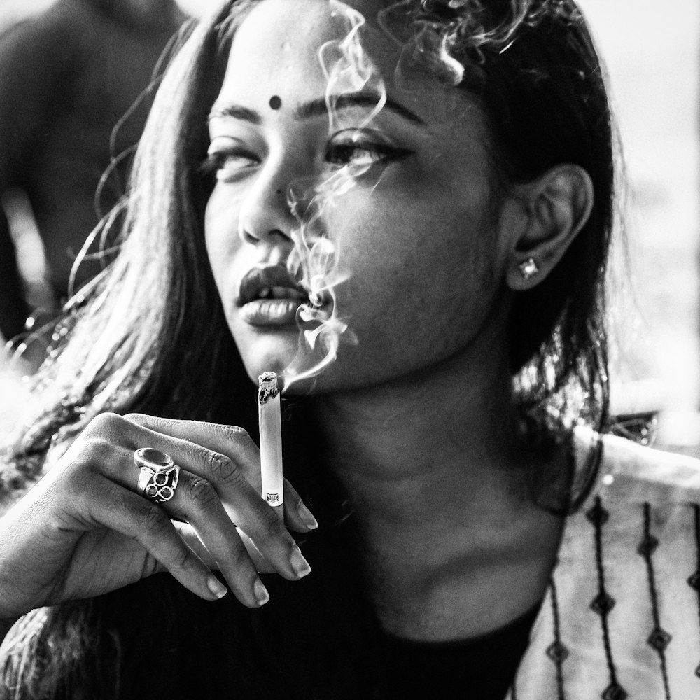 greyscale photo of woman holding cigarette