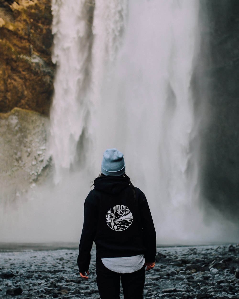 person standing near waterfalls during daytime