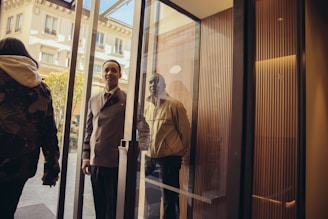 A smiling concierge assisting a guest with their luggage at a stylish entrance.