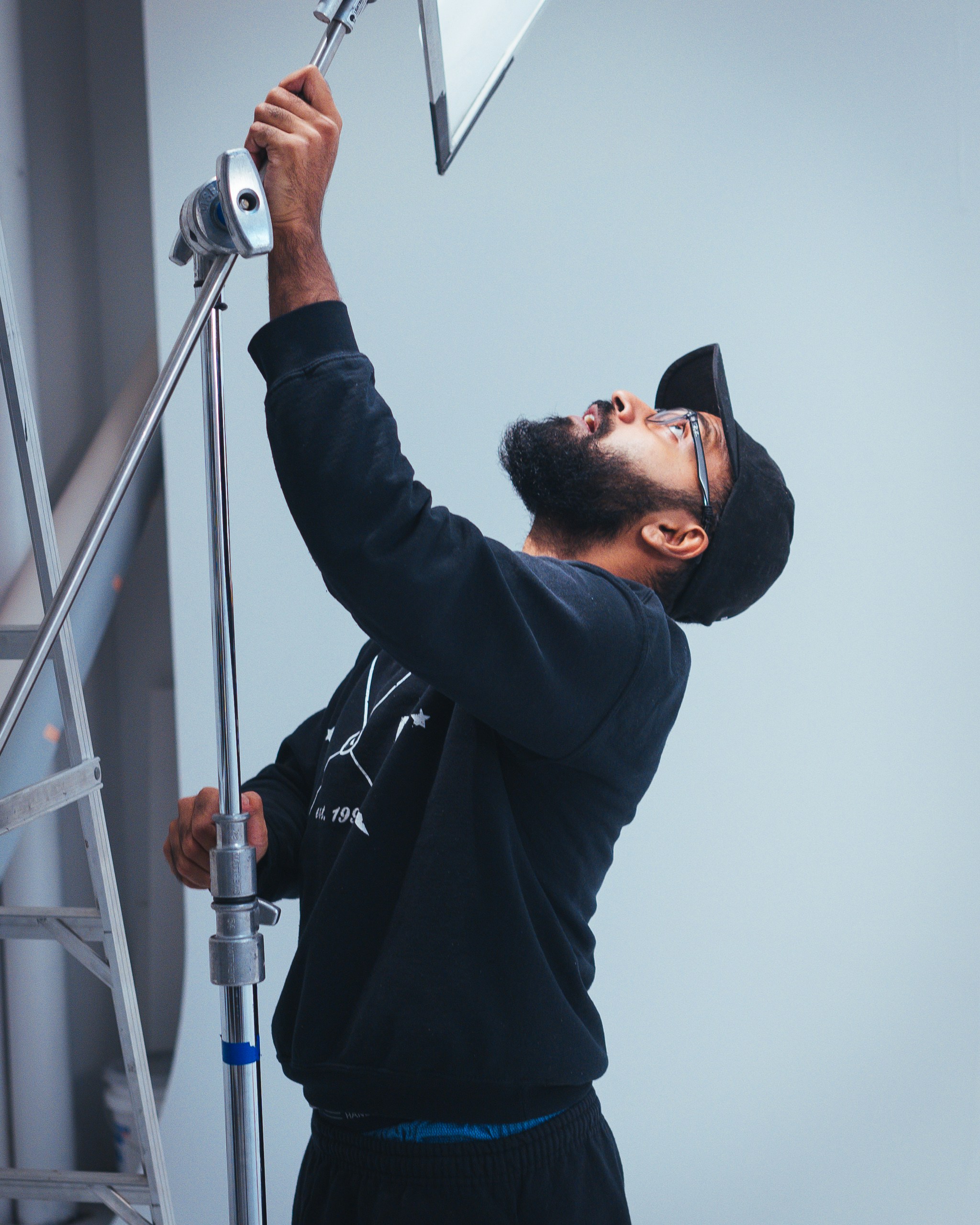 灰色と黒のカメラを持つ黒いパーカーと黒い帽子の男