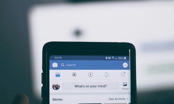 Personne tenant un smartphone ouvert sur l'application Facebook