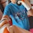 A person wearing a blue t-shirt with the words 'move smart' is holding a black-and-orange punching mitt and wearing boxing gloves. The background shows exercise equipment.
