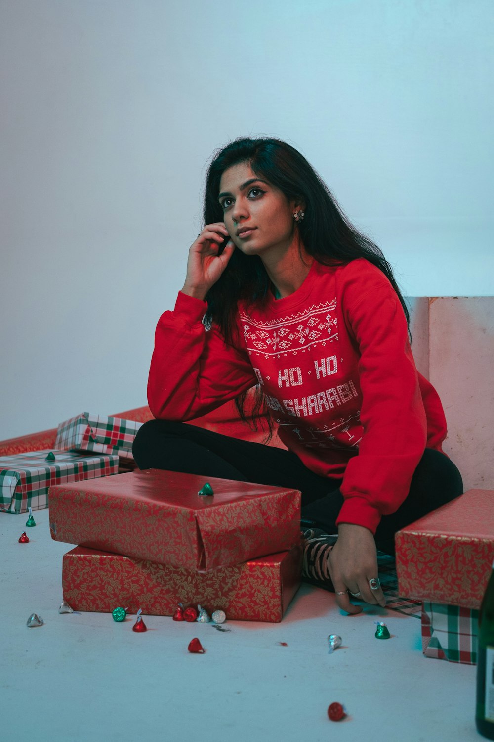 Une femme en pull rouge assise sur une pile de cadeaux