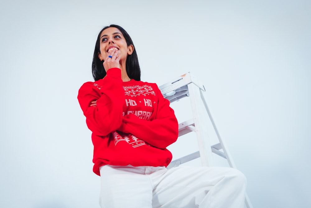 femme en pull rouge debout tout en souriant