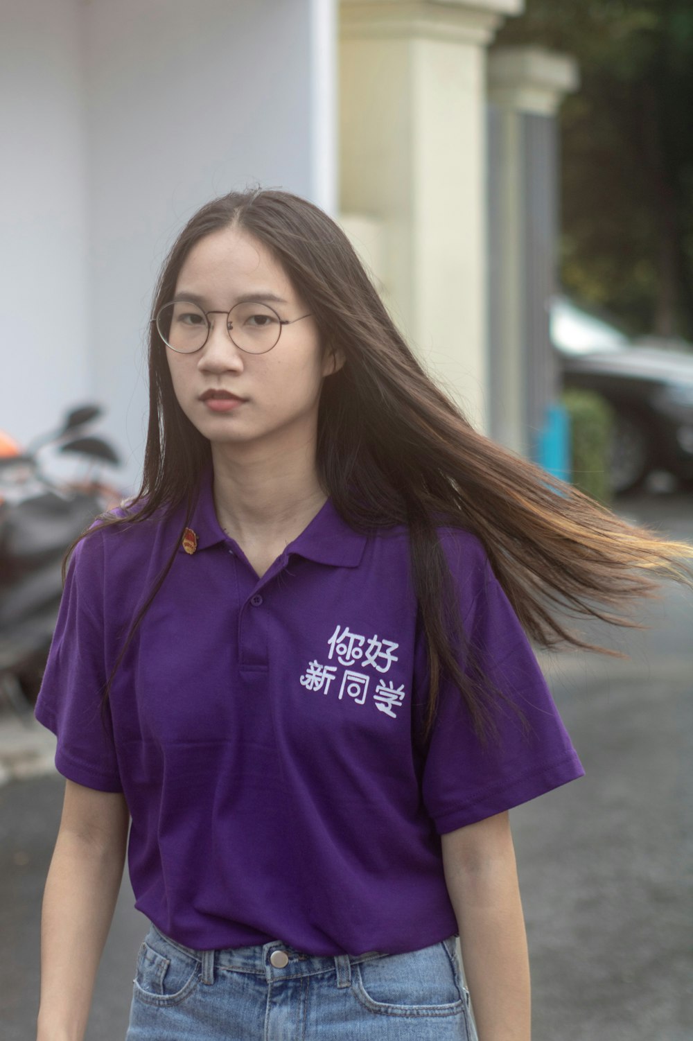 woman wearing purple polo shirt standing near white concrete building