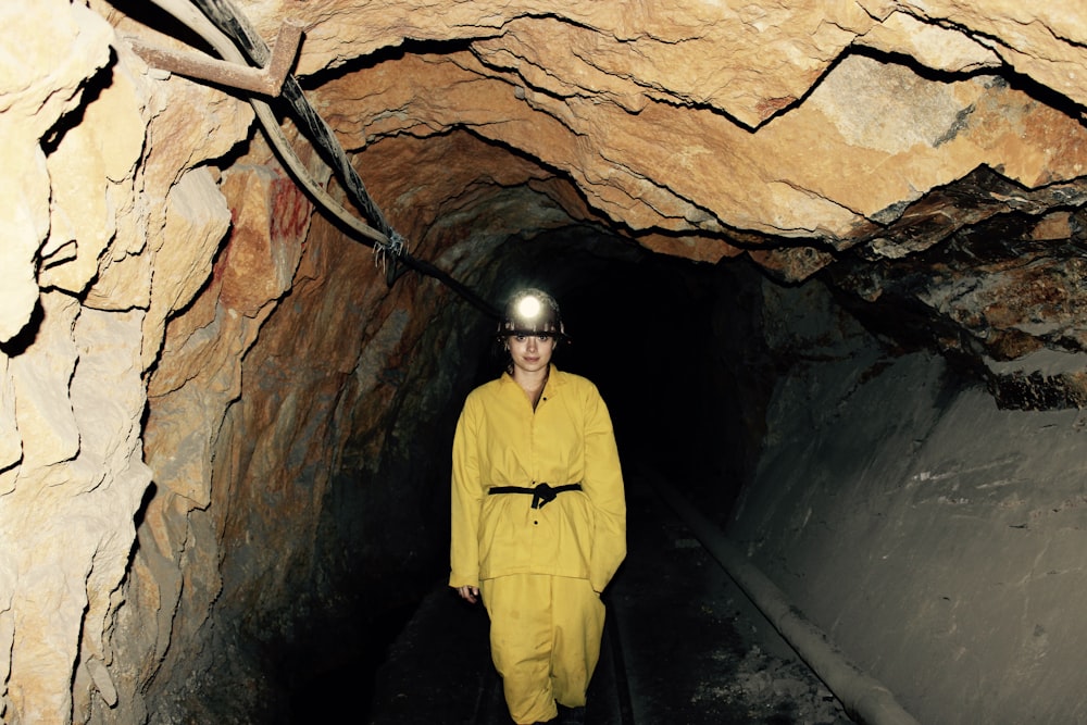 femme vêtue d’une salopette jaune debout sous la grotte