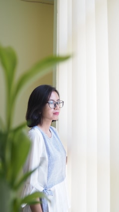 A calm leader sitting thoughtfully in a sunlit room filled with plants.