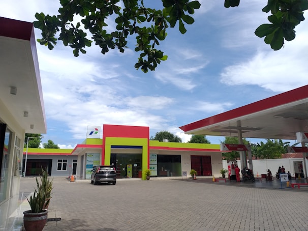 A newly constructed fuel station with sleek canopies and polished forecourt surface under bright daylight.