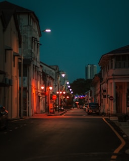 Evening shot of a quiet street lined with elegant homes under warm street lamps.