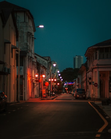Evening shot of a quiet street lined with elegant homes under warm street lamps.
