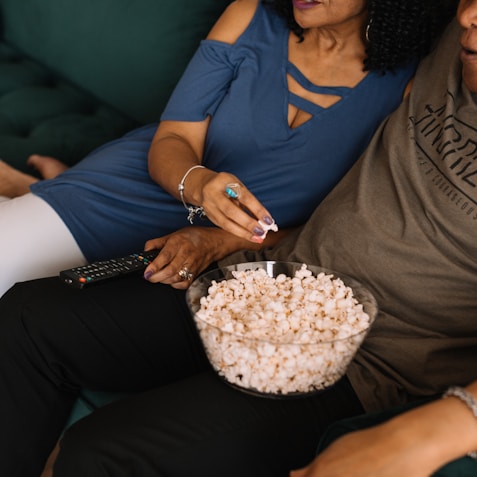 man sitting beside woman while picking popcorn