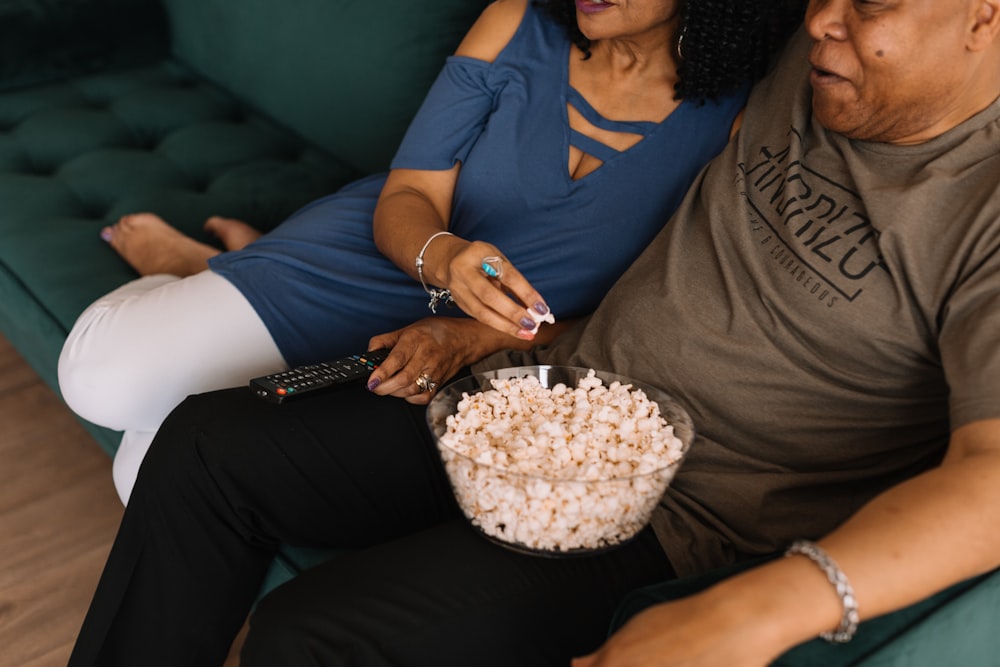 man sitting beside woman while picking popcorn