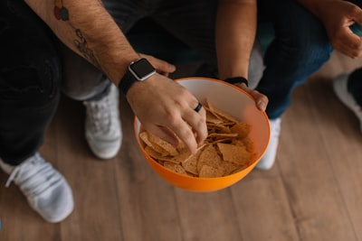 person holding orange bowl with potato chips super bowl google meet background