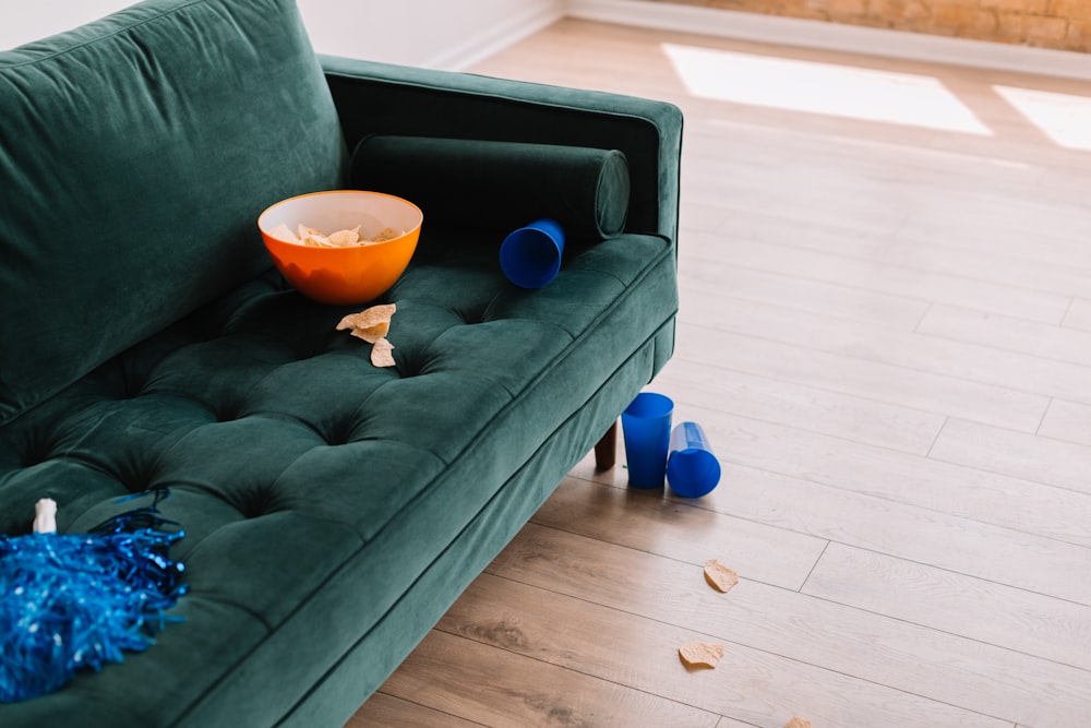 a green couch with a bowl of popcorn on it