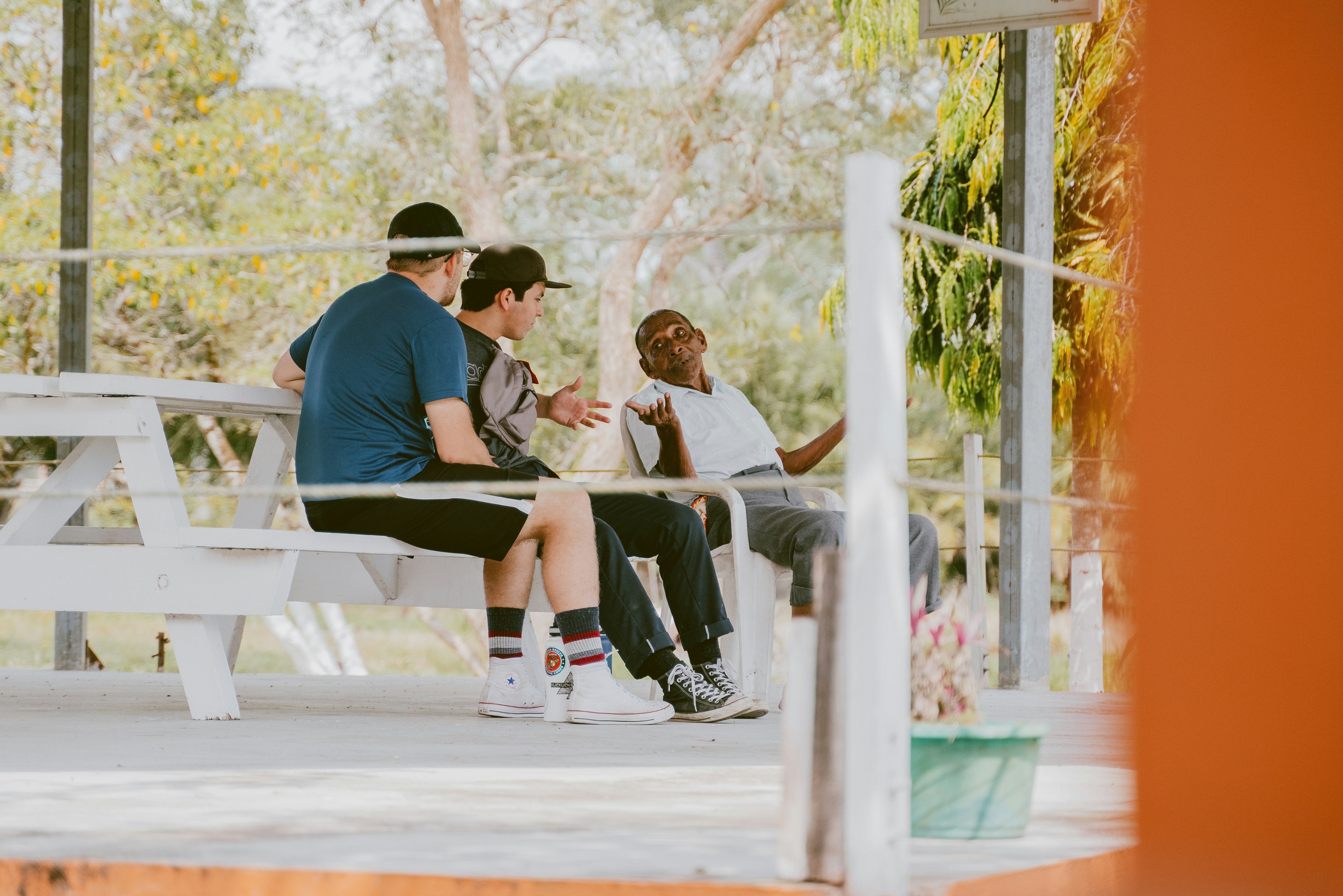 three men sitting on white picnic table white chatting