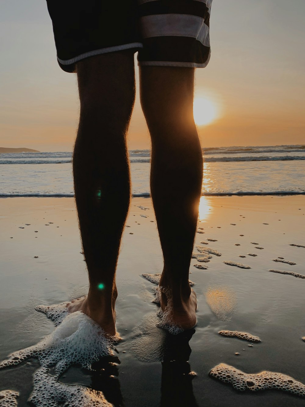 silhouette photography of person standing by the seashore during golden hour