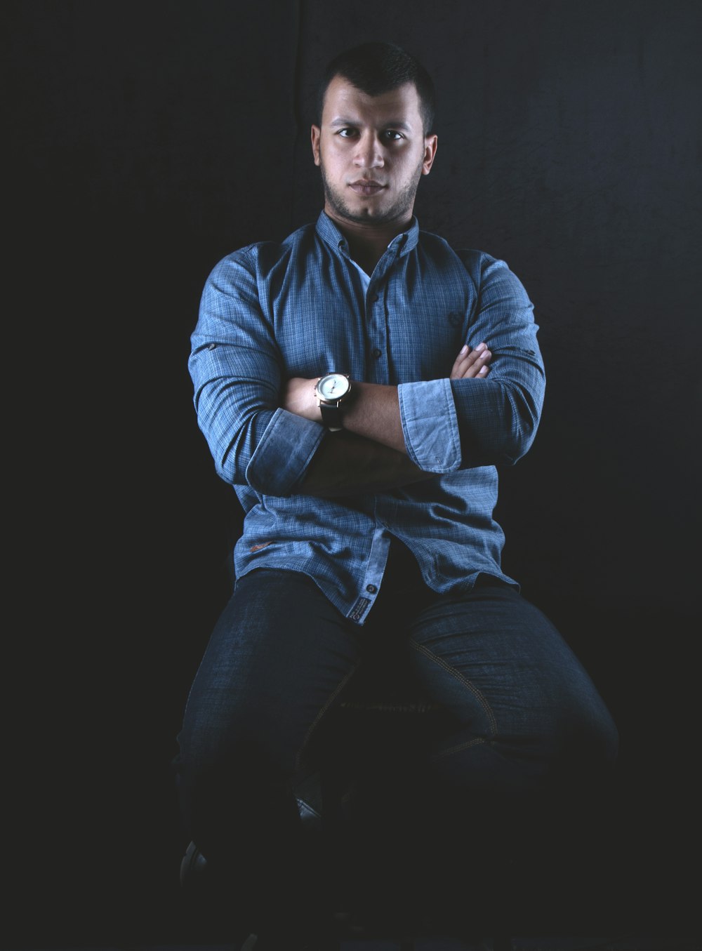 man sitting on stool while crossing both hands