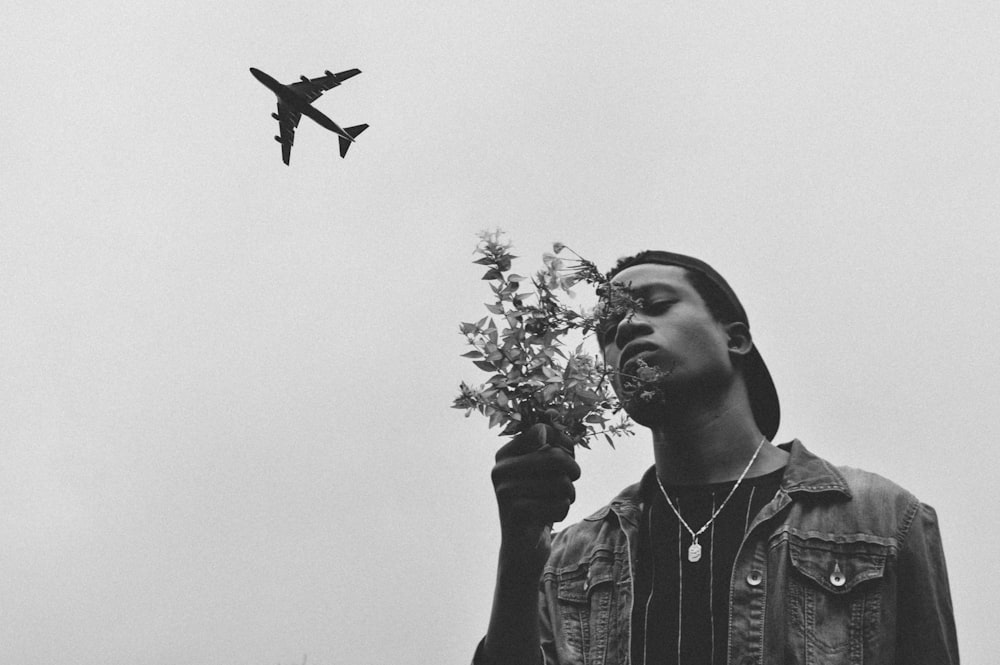 man holding flower with silhouette of plane