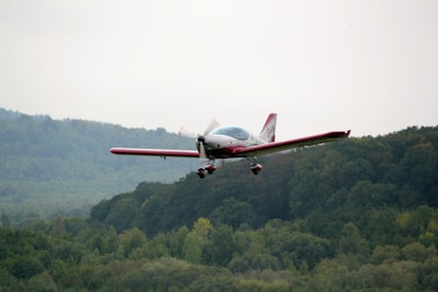 A small private aircraft soaring above lush green landscapes under a clear blue sky.