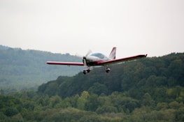 A small aircraft flying over scenic hills and rivers.
