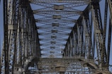 A detailed close-up of a steel bridge truss under bright daylight, showcasing structural connections.