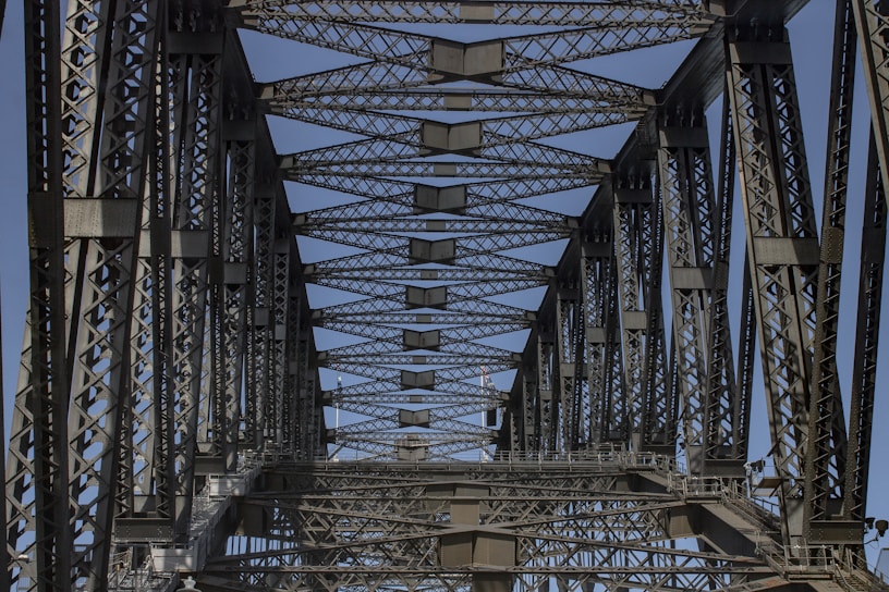 A close-up view of a steel bridge truss under bright daylight, showcasing intricate engineering details.