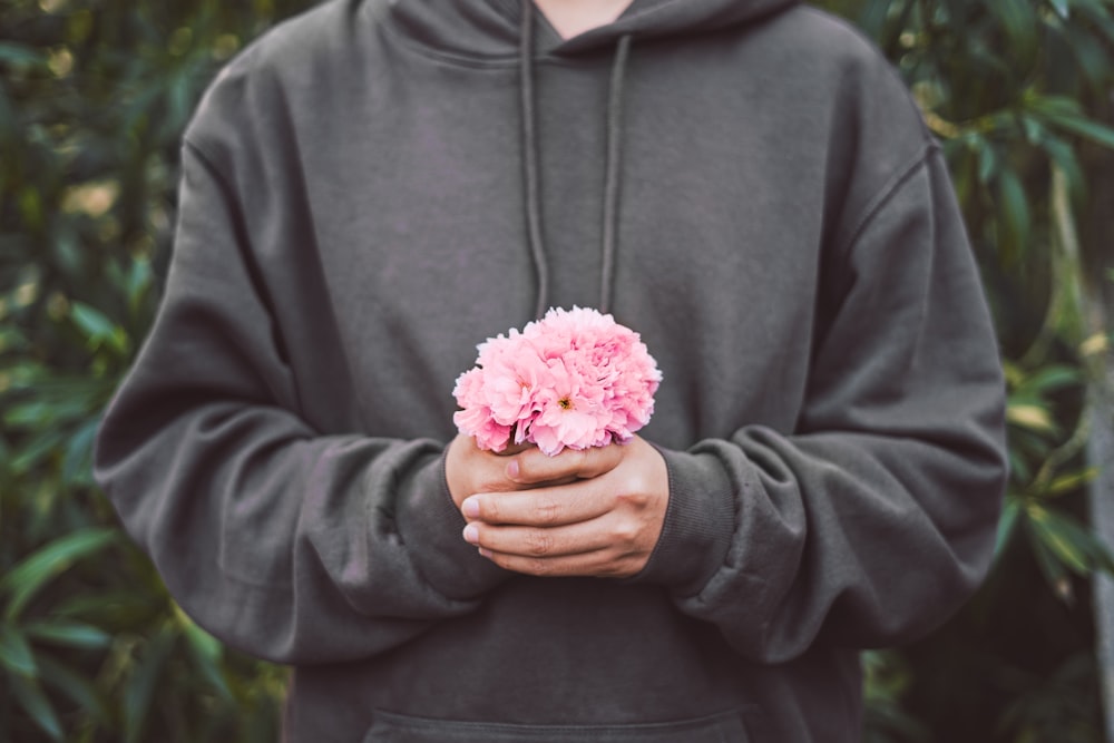 personne tenant des fleurs roses