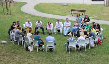 circle of people sitting on chair on grass fiedl