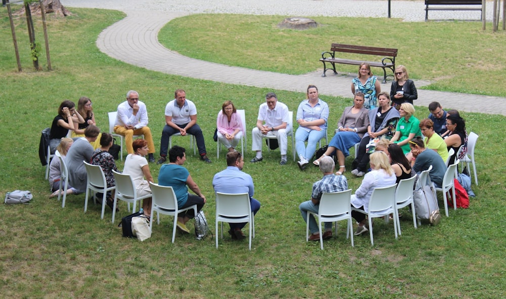 circle of people sitting on chair on grass fiedl