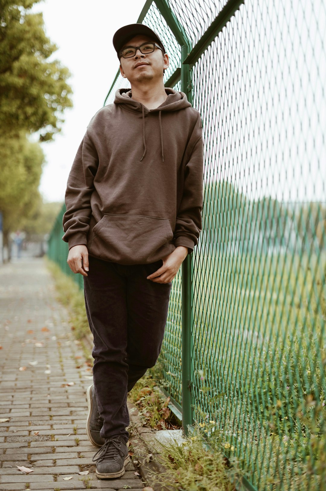 man in gray hoodie standing on sidewalk during daytime