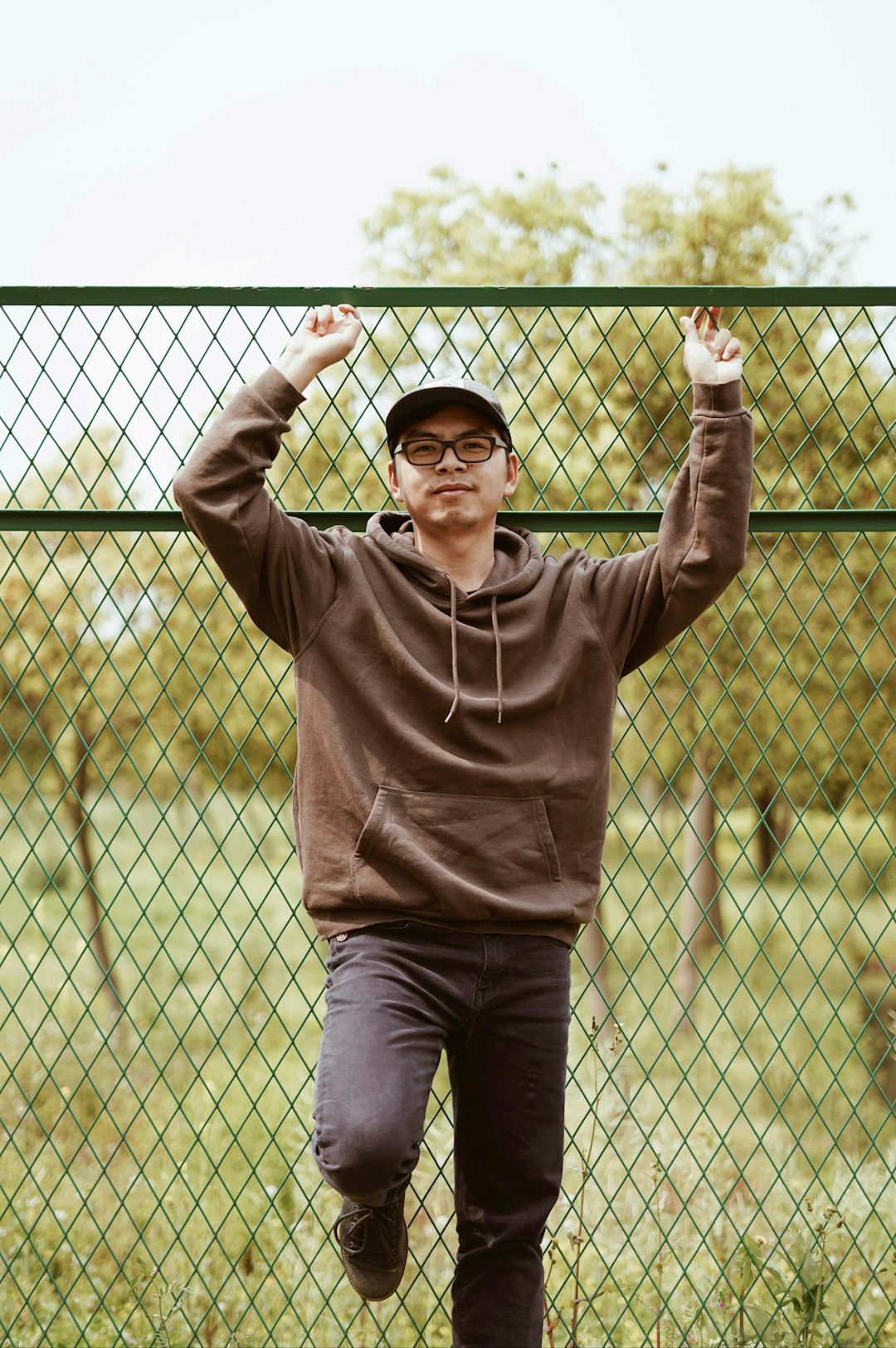 man in brown hoodie standing near fence