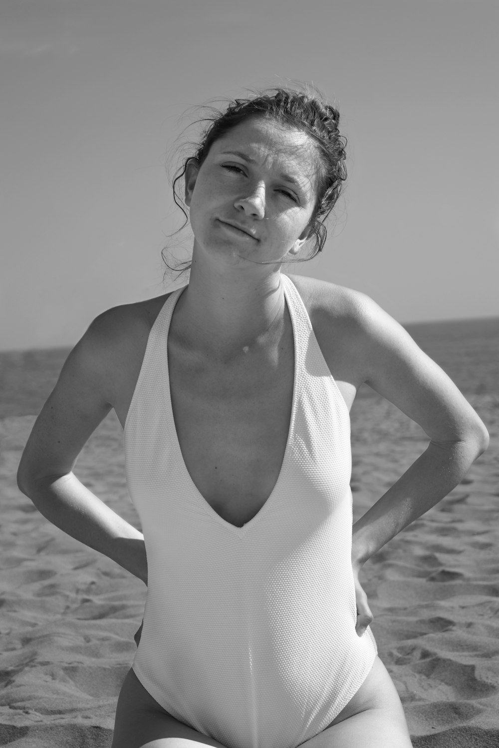 pregnant woman sitting on sand with both arms akimbo