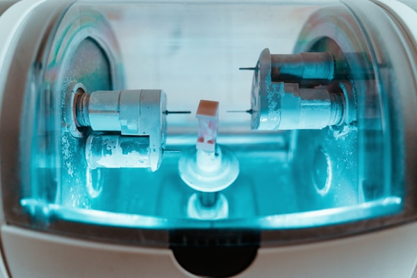 A technician working with dental CAD/CAM equipment in a bright lab.
