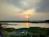 A technician installing water quality sensors by a riverbank at sunrise.