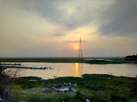 A technician installing water quality sensors by a riverbank at sunrise.