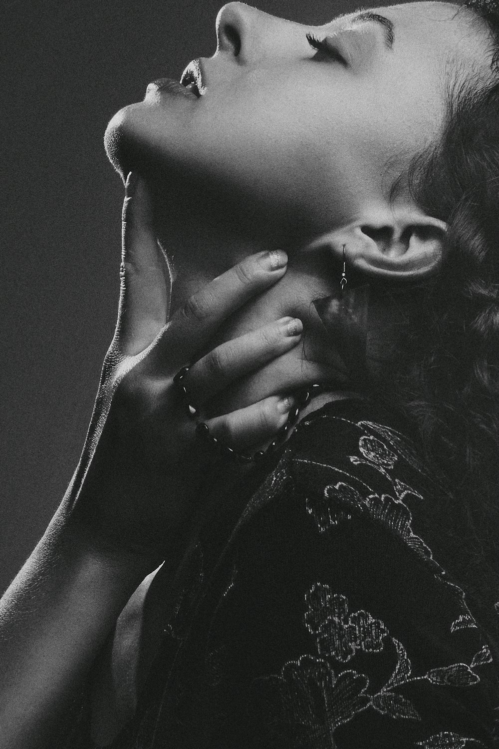 Graustufenfotografie einer Frau, die ihren Hals hält