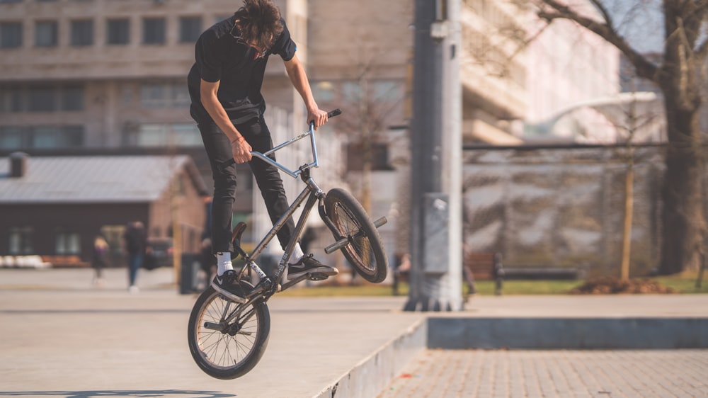 man performing bike stunk near electric post during daytime