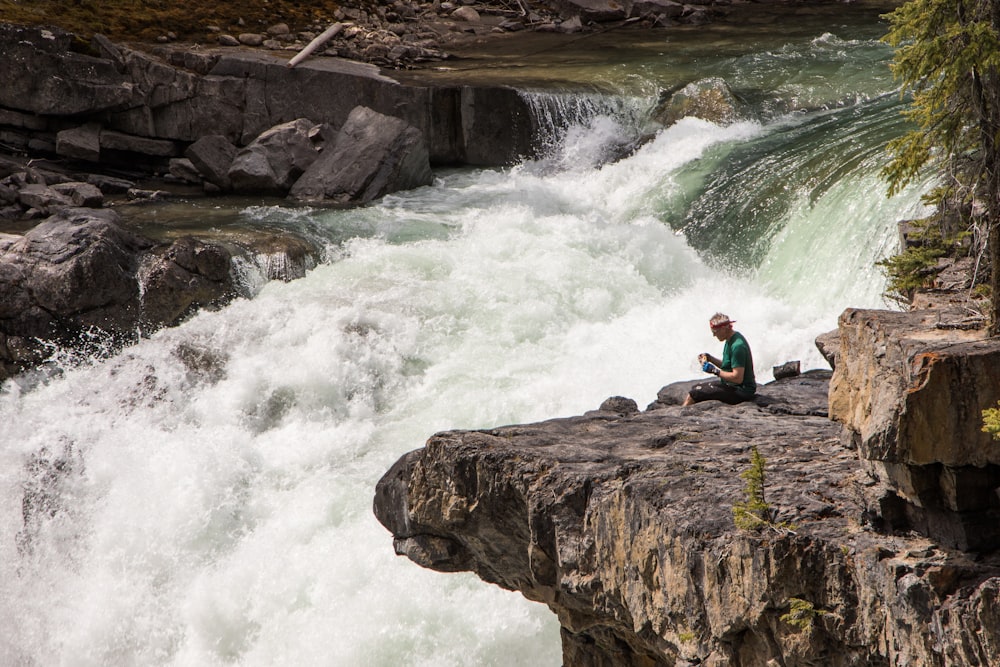 man sitting beside river during daytime