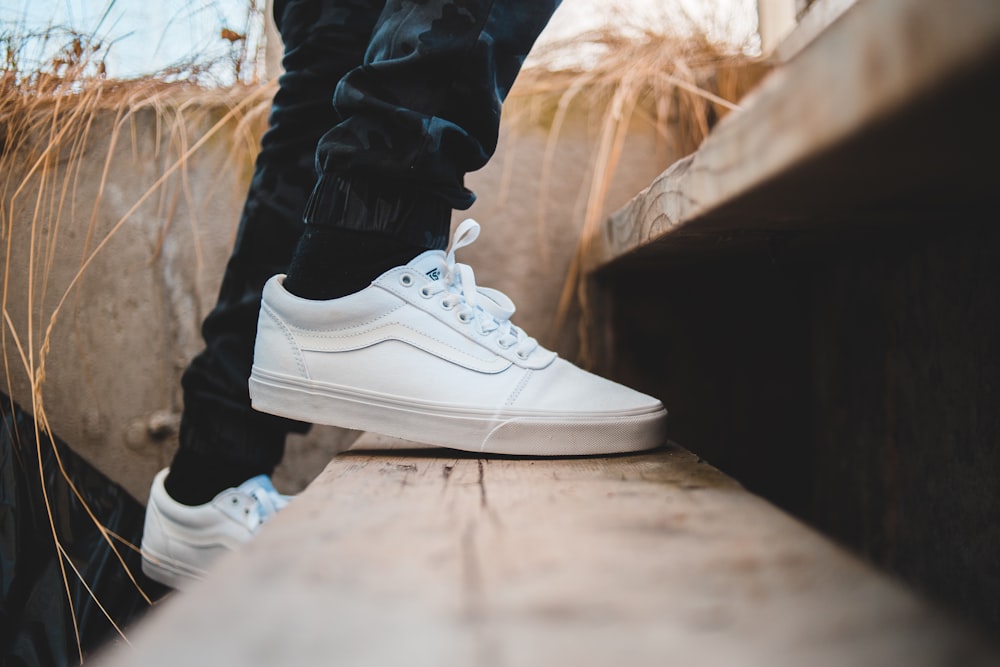 person wearing black socks and black-and-white Vans shoes sitting on black  rod photo – Free Apparel Image on Unsplash