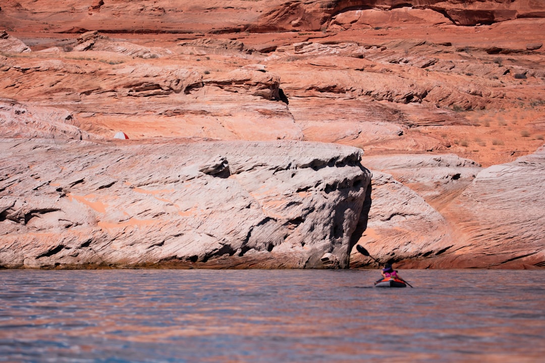 person paddling his kayak heading towards rock formation