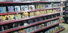 Shelves filled with various toy figurines and boxed sets, organized neatly. The figurines, mostly golden and shiny, depict various characters in dynamic poses. The boxed sets include colorful and detailed packaging featuring imagery of the characters. The overall arrangement is orderly, displaying a collection of collectibles.