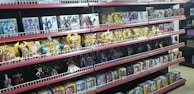 Shelves filled with various toy figurines and boxed sets, organized neatly. The figurines, mostly golden and shiny, depict various characters in dynamic poses. The boxed sets include colorful and detailed packaging featuring imagery of the characters. The overall arrangement is orderly, displaying a collection of collectibles.