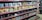 Shelves filled with various toy figurines and boxed sets, organized neatly. The figurines, mostly golden and shiny, depict various characters in dynamic poses. The boxed sets include colorful and detailed packaging featuring imagery of the characters. The overall arrangement is orderly, displaying a collection of collectibles.