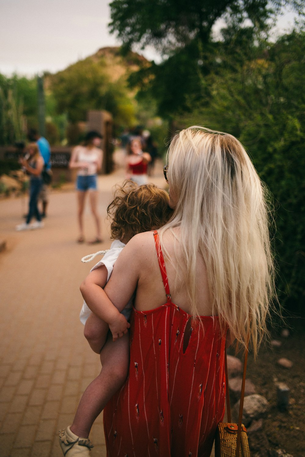 woman carrying baby standing on brown pathway