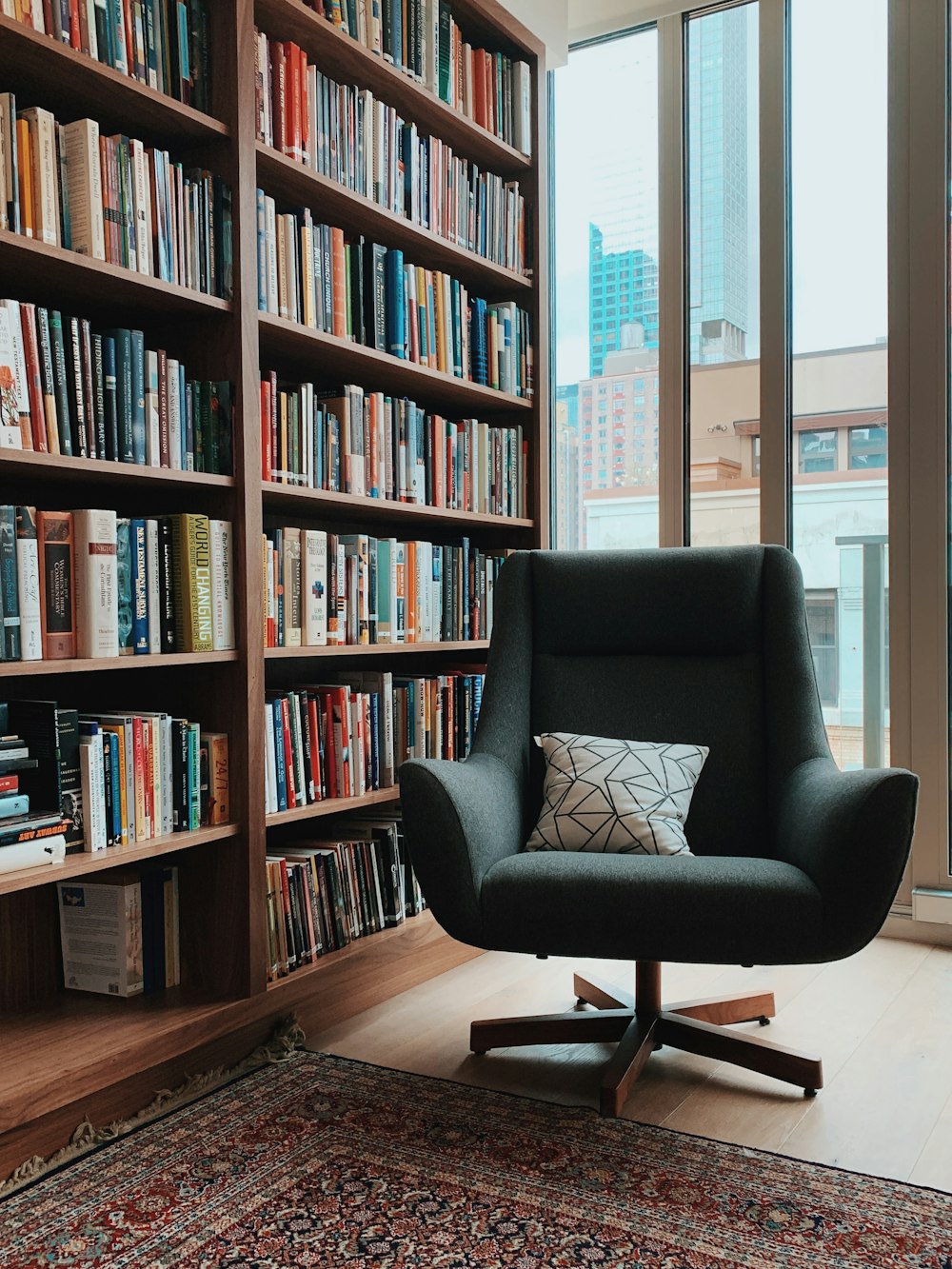 gray fabric padded rolling armchair near books